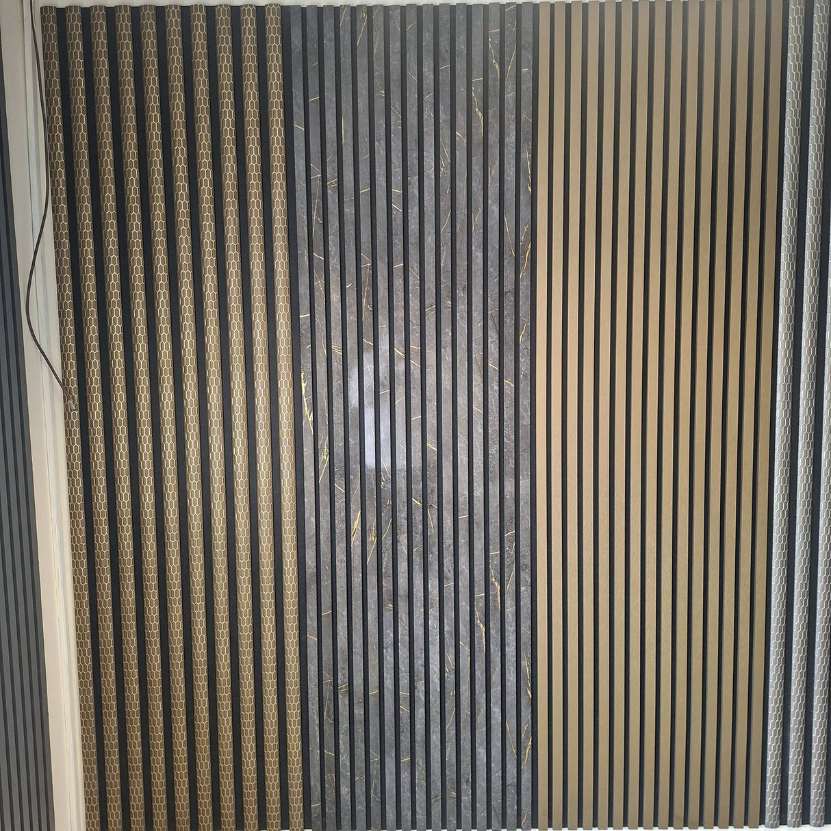 A wall-mounted decorative slatted panel with vertical wood-look and dark textured stripes, installed in a room with a white ceiling and gray floor. A small 'Galaxy A56 5G' watermark is visible at the bottom left.
