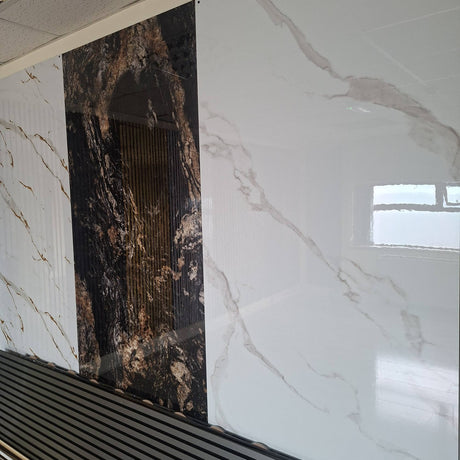 Large-format wall tiles shown in a showroom setting, featuring a white marble-look pattern with gray veining on the right and a dark brown and black marble-look panel on the left.