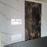 Large decorative wall panels showing marble-like textures, with a white panel featuring gold veining on the left and a dark brown/black panel with coppery veining in the center-right, installed against a wall above a slatted black surface.