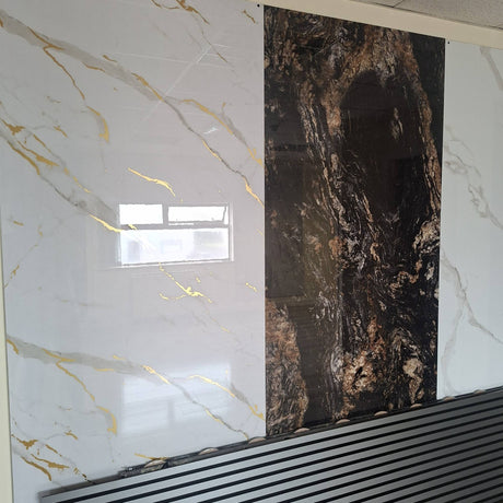 Large decorative wall panels showing marble-like textures, with a white panel featuring gold veining on the left and a dark brown/black panel with coppery veining in the center-right, installed against a wall above a slatted black surface.