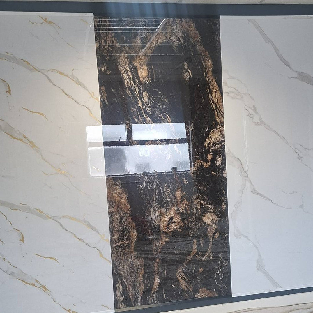 A large rectangular sample of dark brown and black marble-patterned tile or stone paneling is shown vertically, flanked by white marble-patterned panels on both sides. The center sample is still wrapped in protective plastic, with a window visible in the middle.